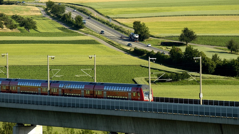 Eine Regionalbahn fährt über eine Eisenbahnbrücke durch eine vorwiegend grüne Landschaft Eine Regionalbahn fährt über eine Eisenbahnbrücke durch eine vorwiegend grüne Landschaft